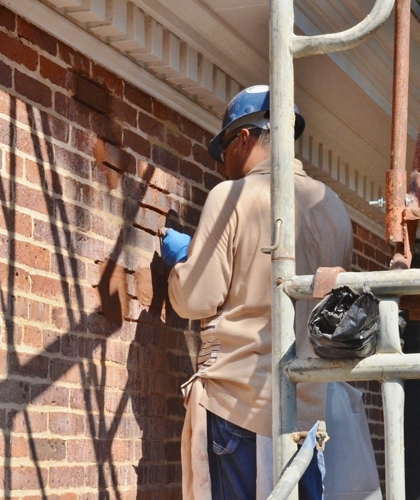 worker grinds out damaged mortar to prepare to re-point masonry.