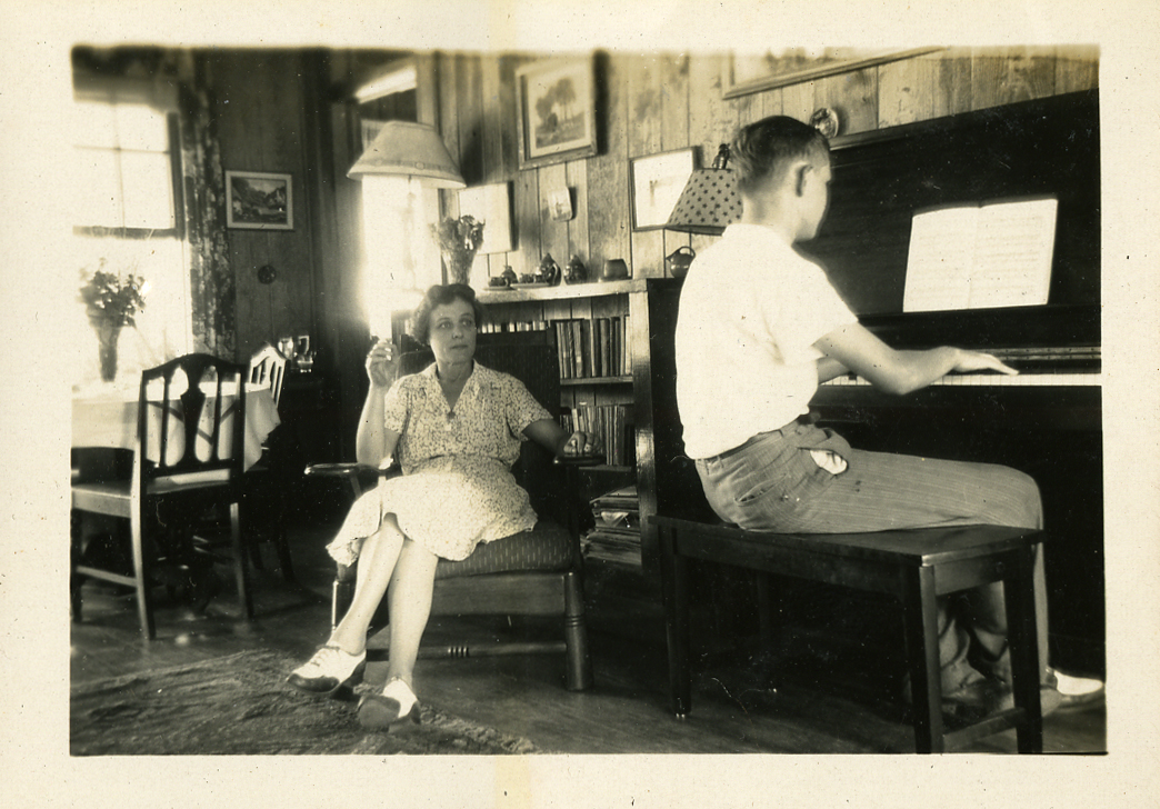 Anthony Jensen plays the piano in the living room of the Burr Cottage for his mother, ca. 1940.